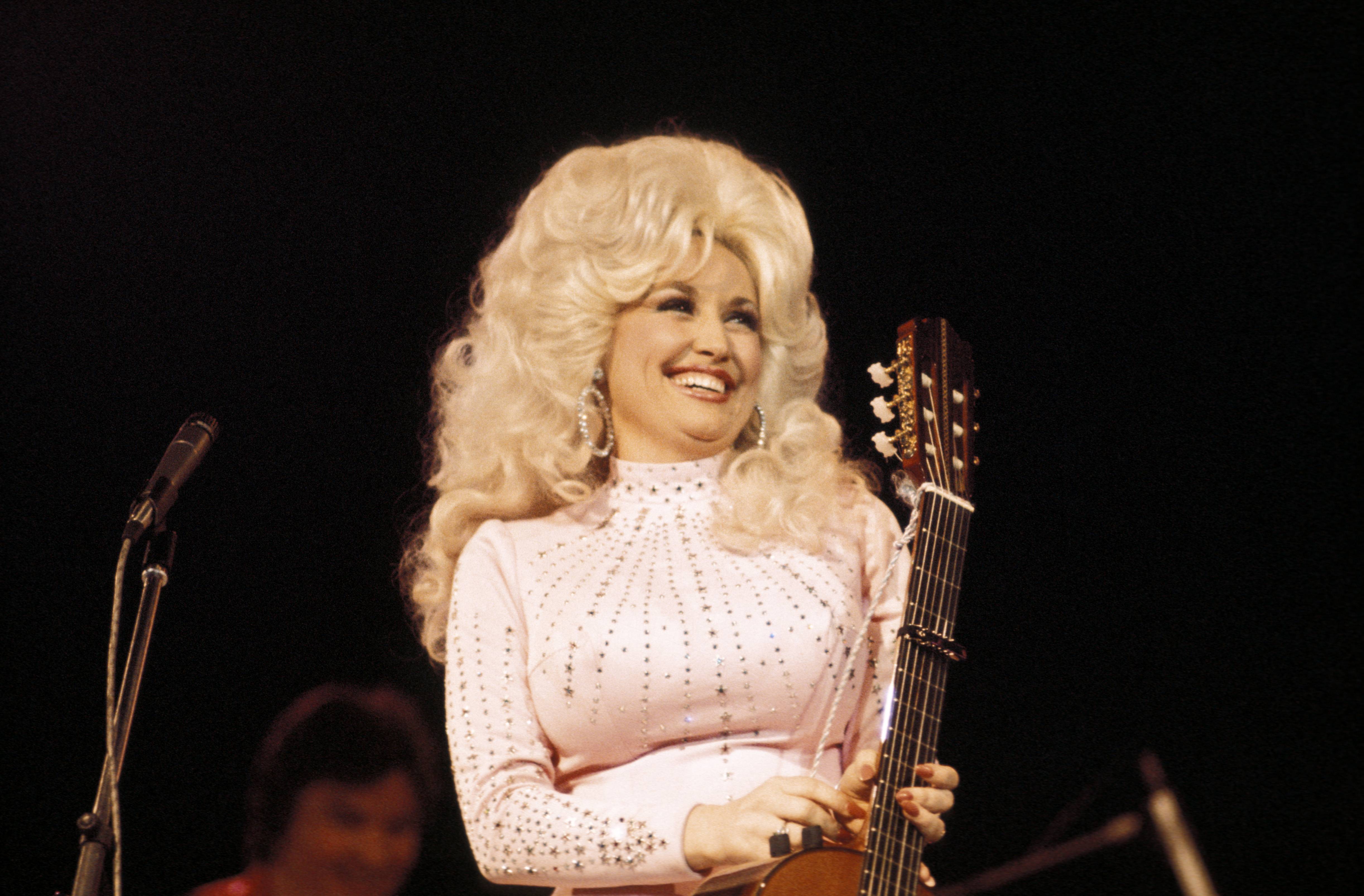 Dolly Parton on stage with a guitar.