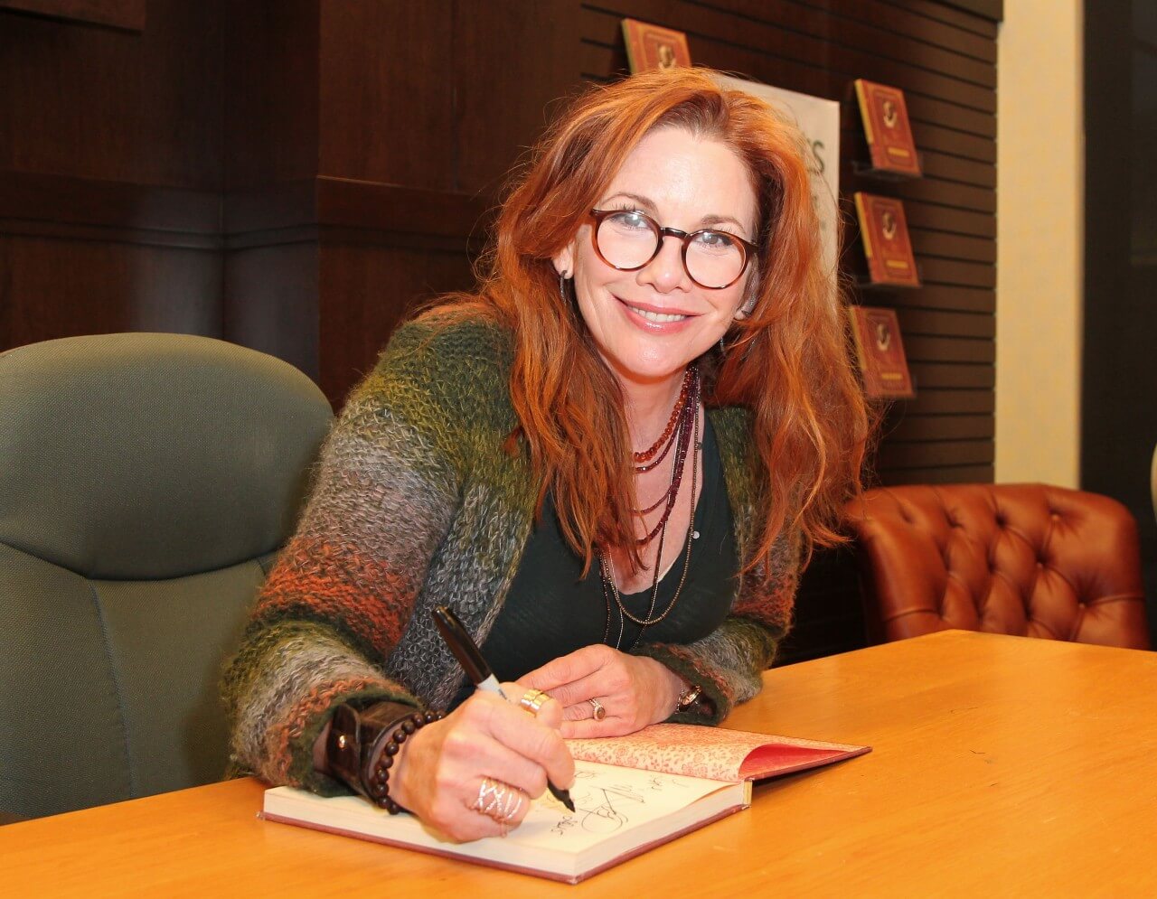 Melissa Gilbert signs a book during an event.