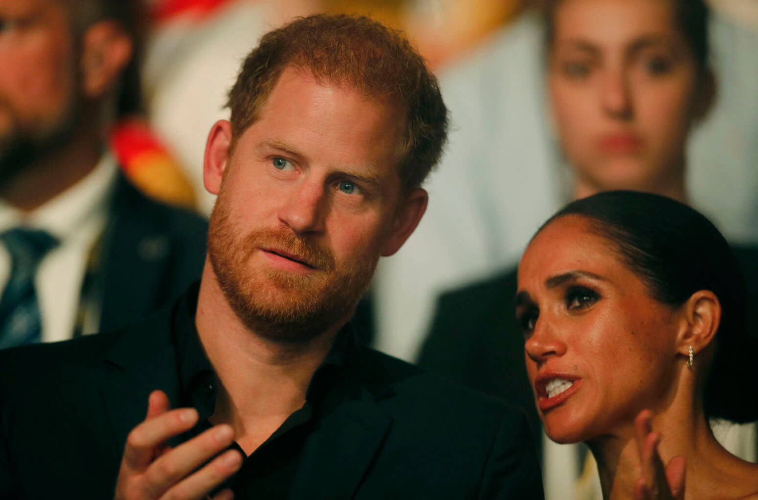 A close-up of Meghan Markle talking while Prince Harry is leaning in to hear her at the Invictus Games