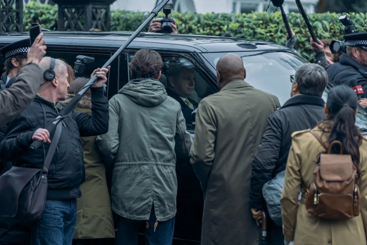 Michael Sheen as Prince Andrew in an SUV surrounded by paparazzi