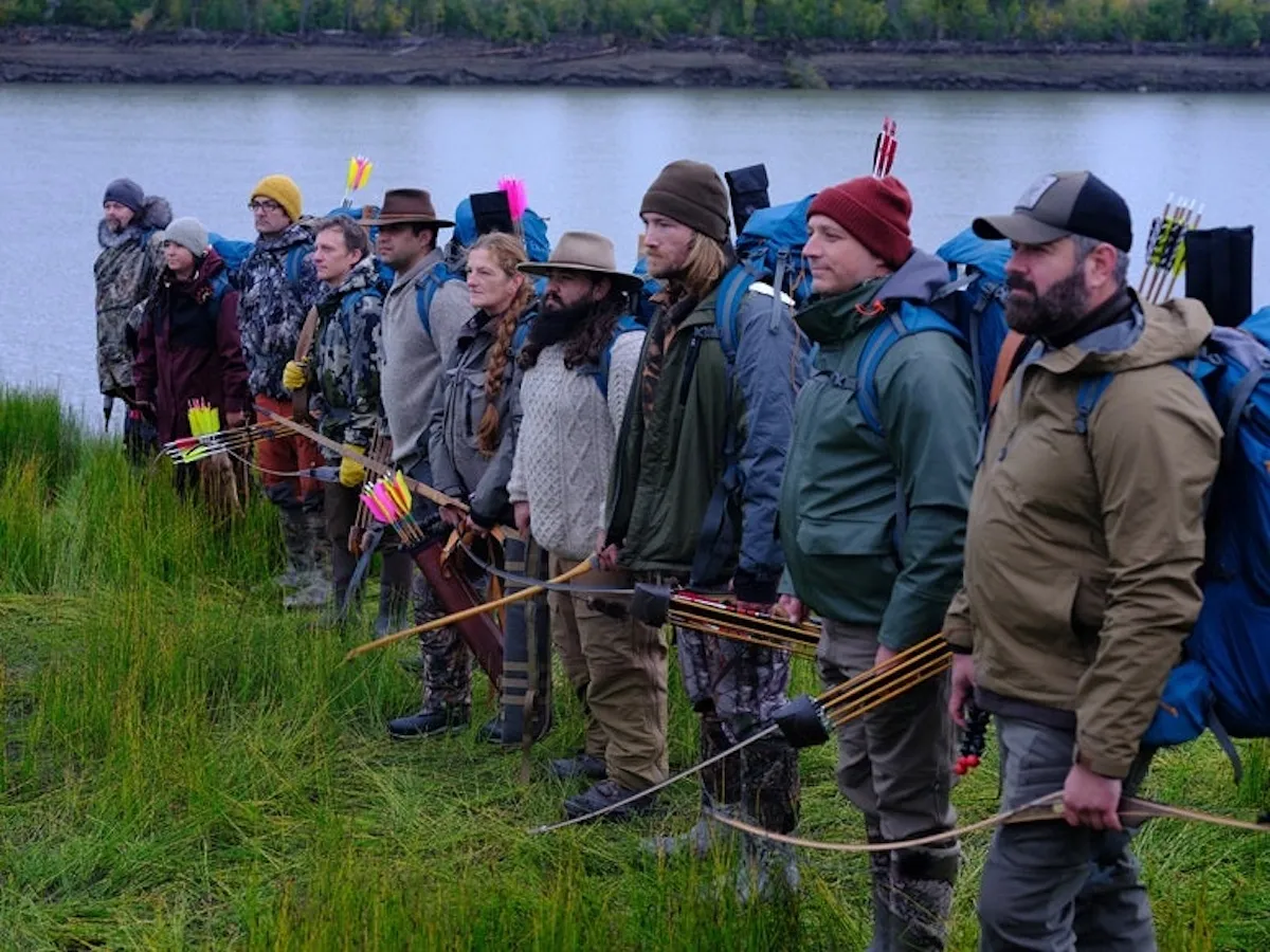 Alone Season 11 cast members standing in a row by a lake