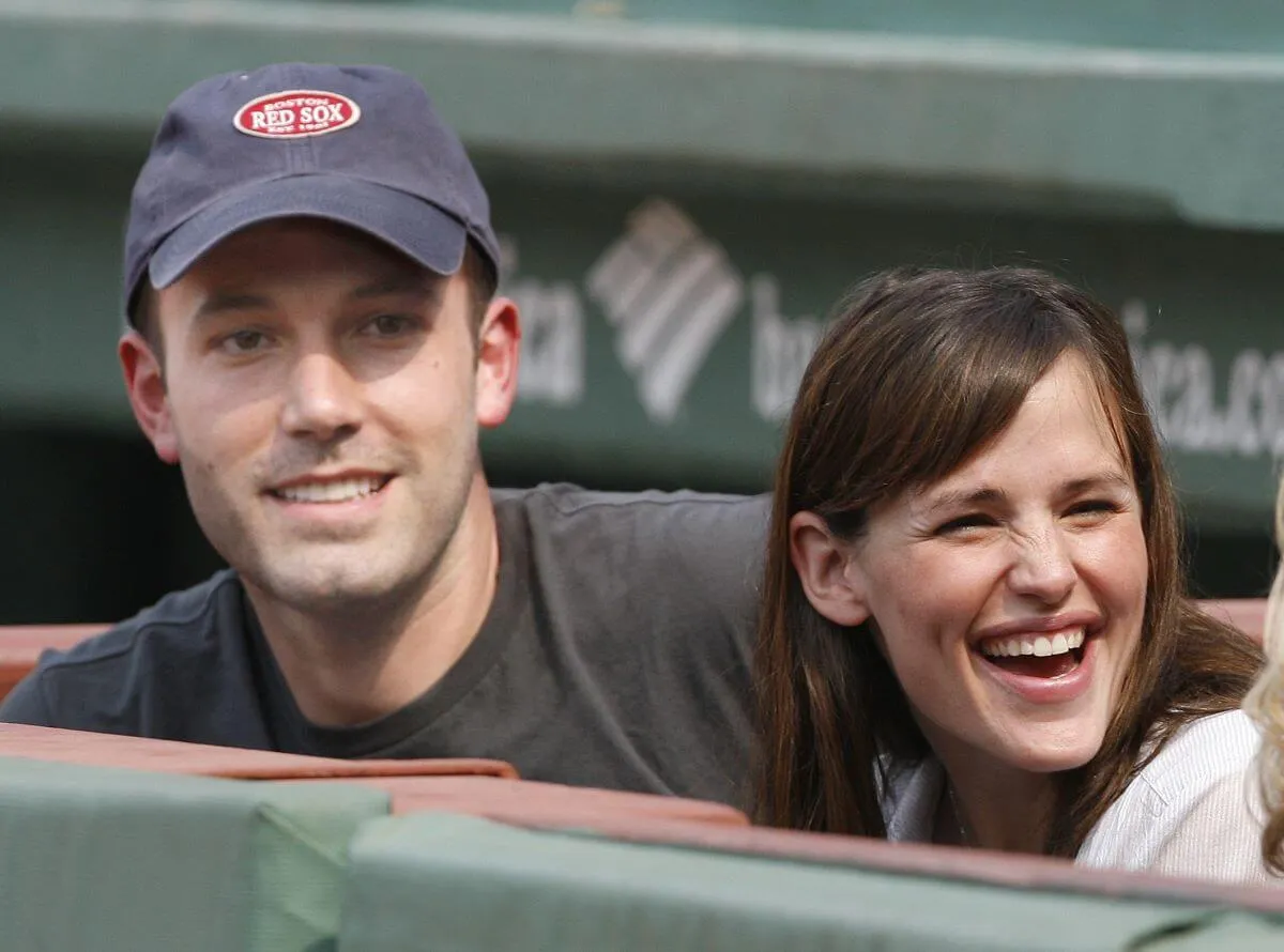 Ben Affleck wears a baseball hat and sits next to Jennifer Garner at a Red Sox game.