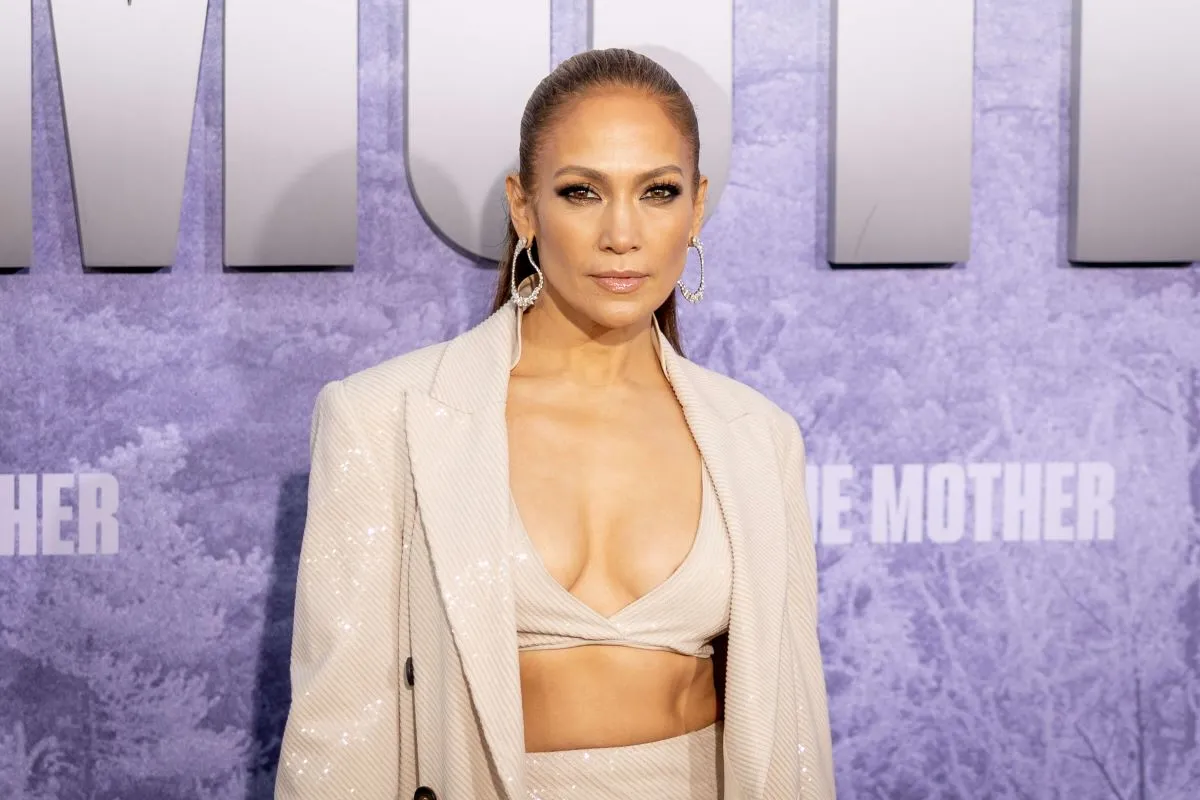 Jennifer Lopez wears a sequined white bra with matching pants and a blazer. Her hair is in a ponytail.