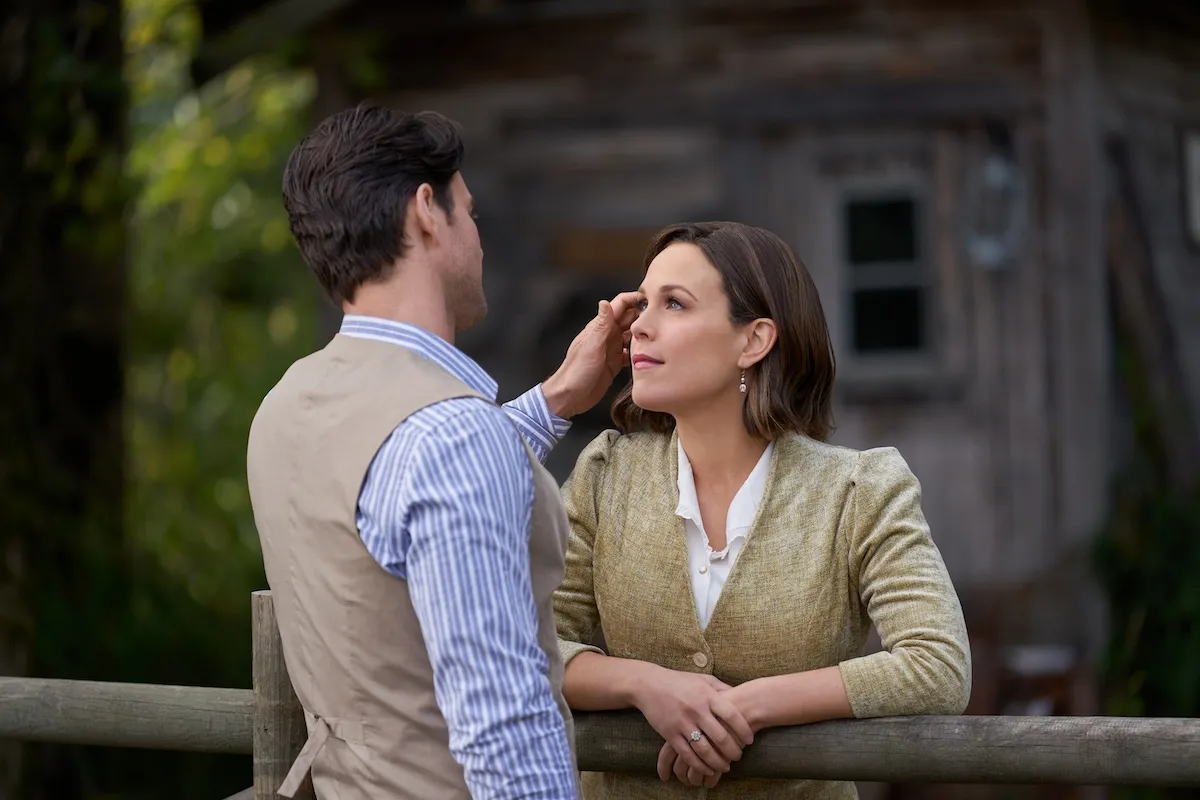 Nathan, with his back to camera, brushes Elizabeth's hair from her face