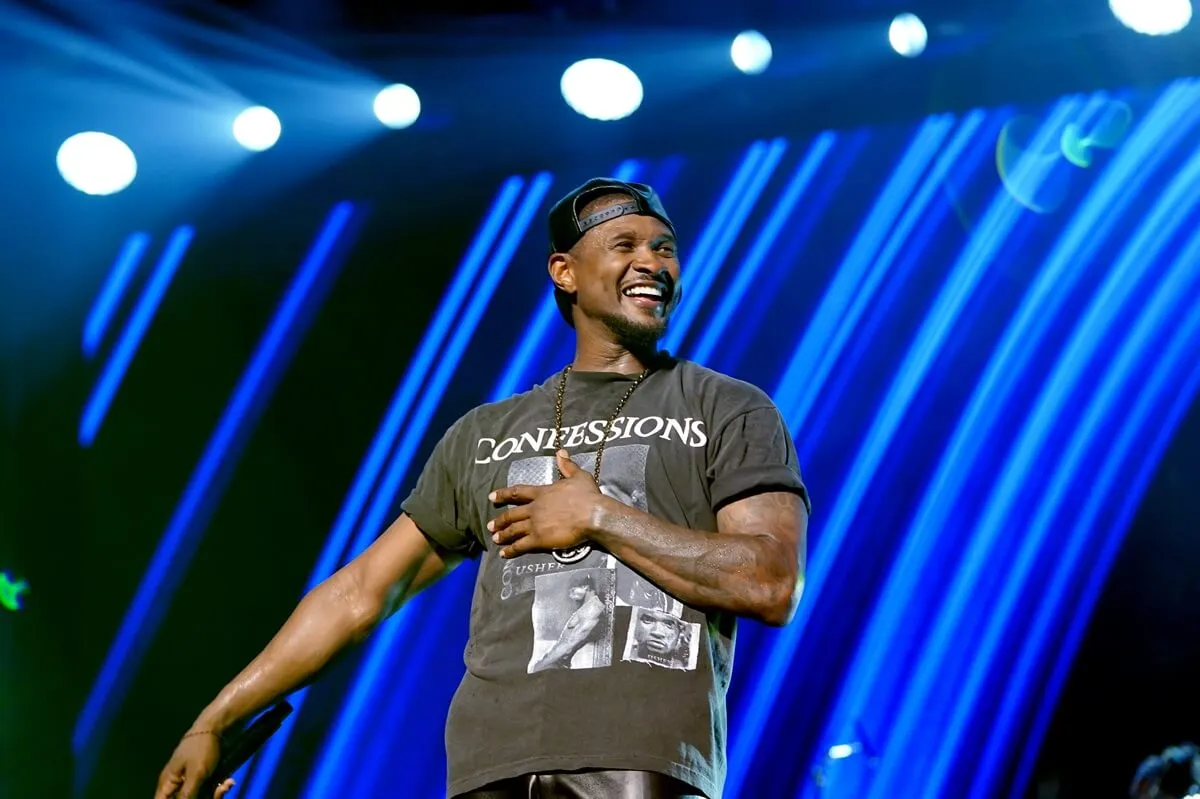 Usher performs onstage during Day 2 of the 2024 ESSENCE Festival in a grey shirt.