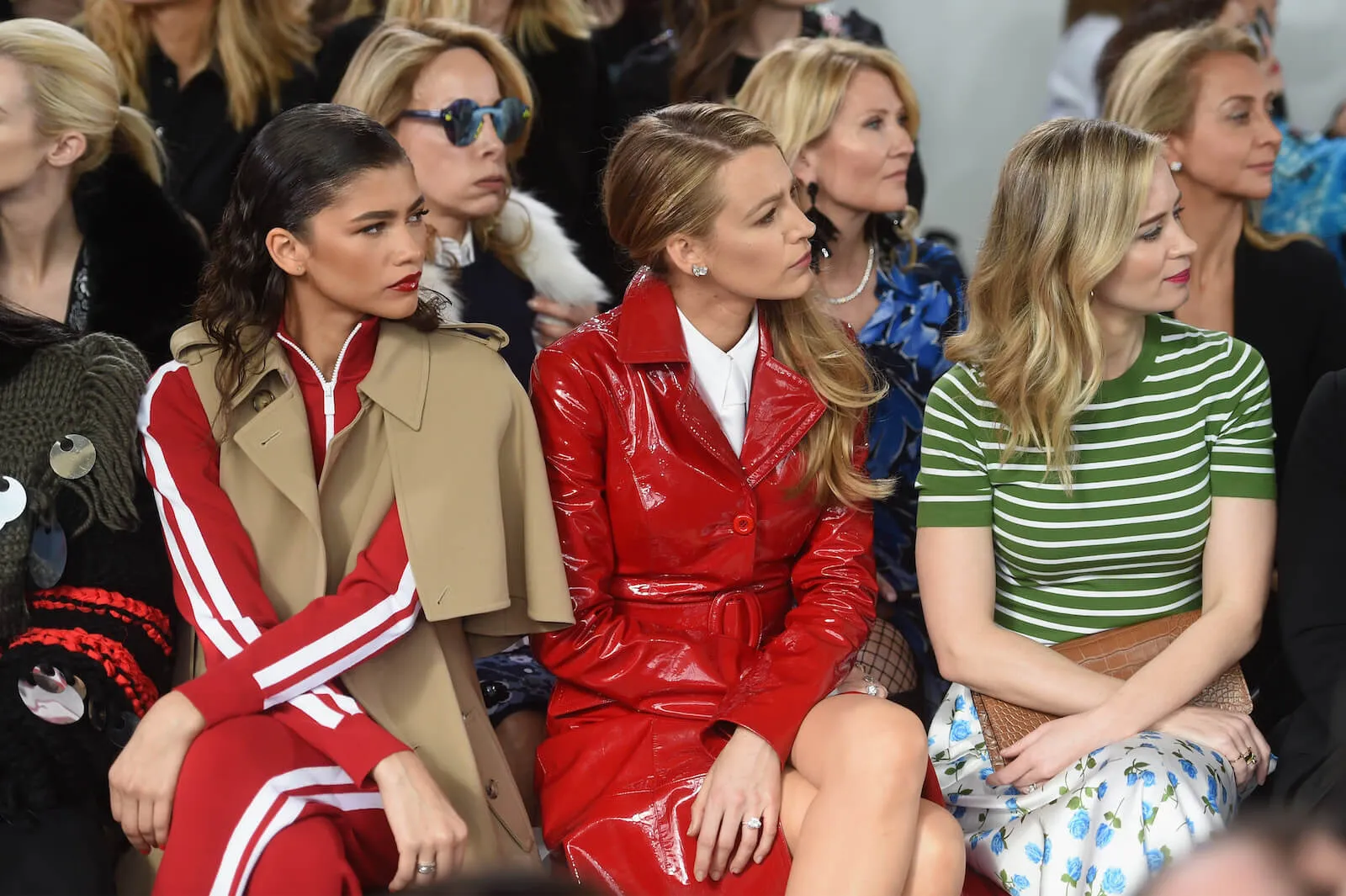 Zendaya, Blake Lively, and Emily Blunt sitting next to each other and looking at the runway at a Michael Kors fashion show in 2018